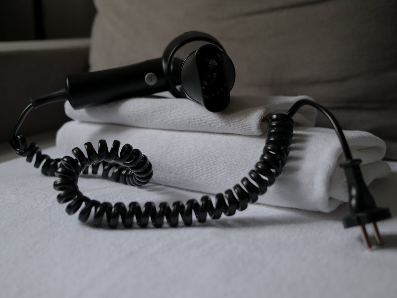 services-03 A coiled hair dryer placed on folded white towels, suggesting a hotel setting.