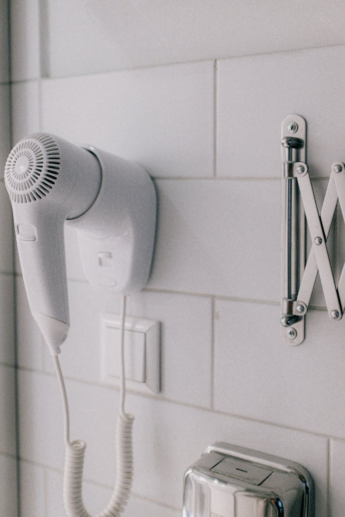 about-01 Clean white wall-mounted hair dryer in a contemporary bathroom setting.
